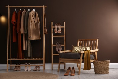 Photo of Modern dressing room interior with clothing rack and comfortable armchair