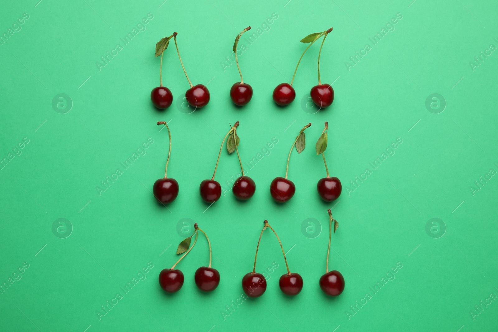 Photo of Tasty ripe cherries with leaves on green background, flat lay