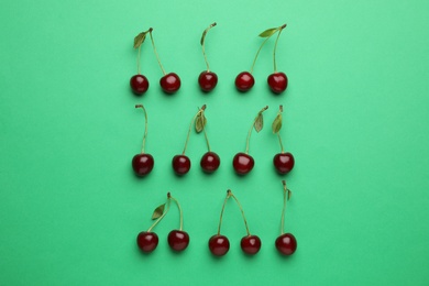 Photo of Tasty ripe cherries with leaves on green background, flat lay