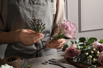 Photo of Florist creating beautiful bouquet at grey table, closeup