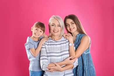 Photo of Beautiful mature woman with daughter and grandchild on color background