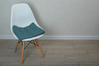 Comfortable chair with cushion near white wall indoors, space for text