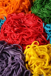 Photo of Rolled spaghetti painted with different food colorings as background, closeup