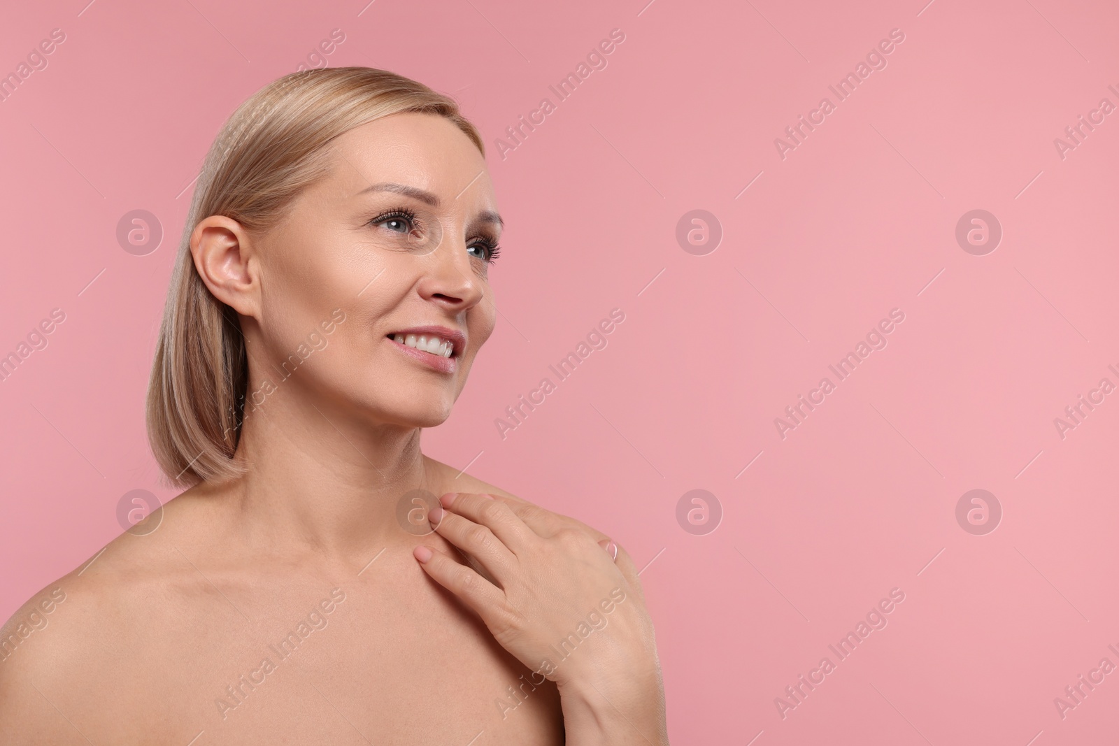 Photo of Beautiful woman touching her neck on pink background. Space for text