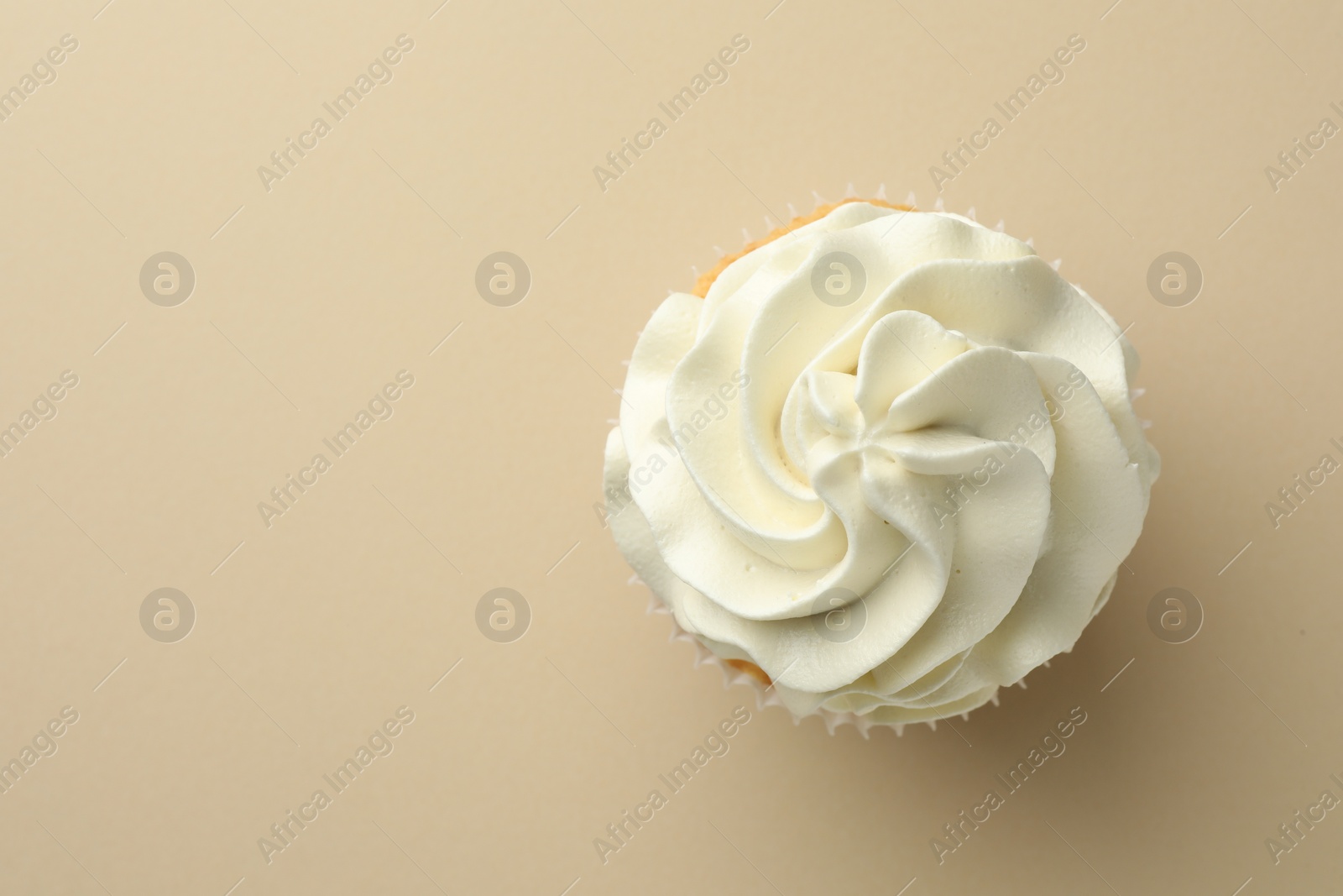 Photo of Tasty vanilla cupcake with cream on beige background, top view. Space for text