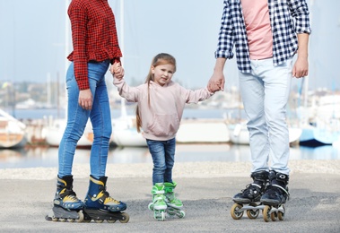 Happy family roller skating on embankment. Active leisure