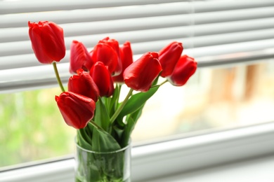 Photo of Bouquet of beautiful tulips in vase near window with blinds