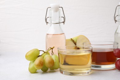 Photo of Different types of vinegar and ingredients on light table, closeup