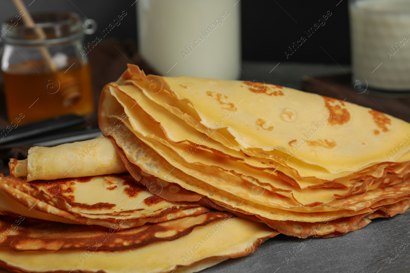 Photo of Fresh thin pancakes on grey board, closeup