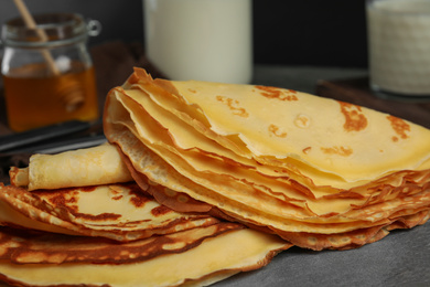 Fresh thin pancakes on grey board, closeup