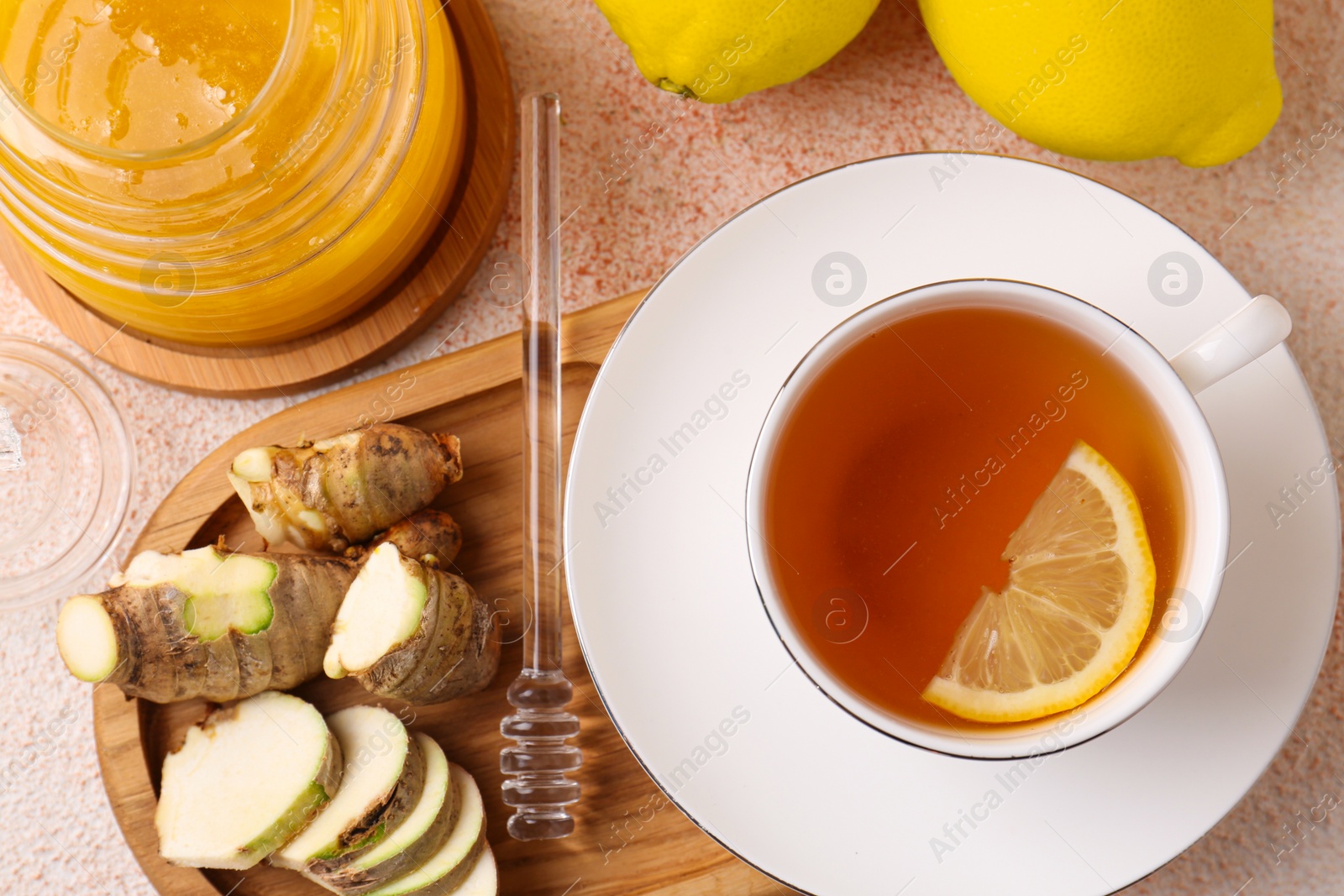 Photo of Tea, honey, lemon and ginger on beige textured table, flat lay