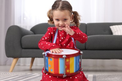 Photo of Little girl playing toy drum at home