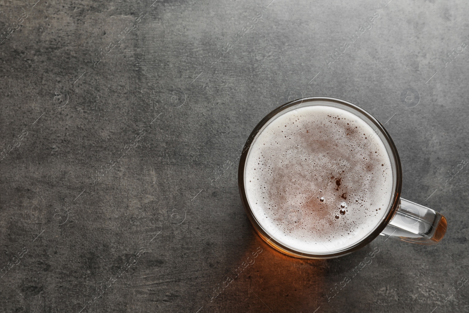 Photo of Glass mug with cold tasty beer on grunge background, top view