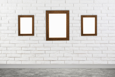 Image of Frames with empty canvases on brick wall in modern art gallery. Space for design