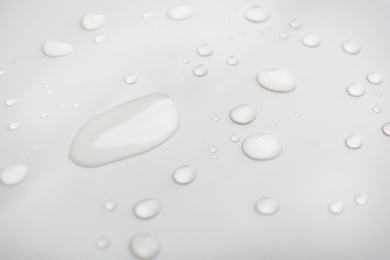 Drops of spilled water on grey background, closeup