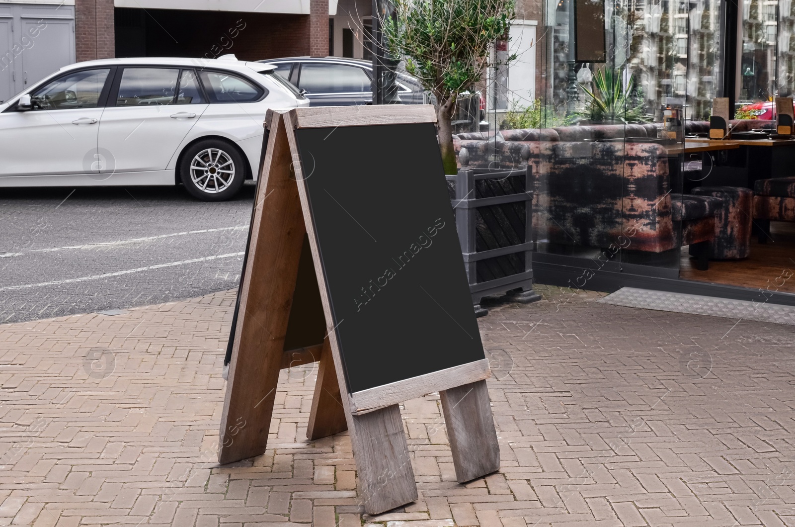 Photo of Black wooden sandwich board near outdoor cafe