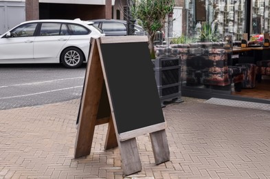 Photo of Black wooden sandwich board near outdoor cafe
