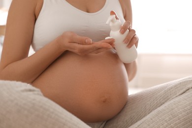 Photo of Young pregnant woman with cosmetic product indoors, closeup