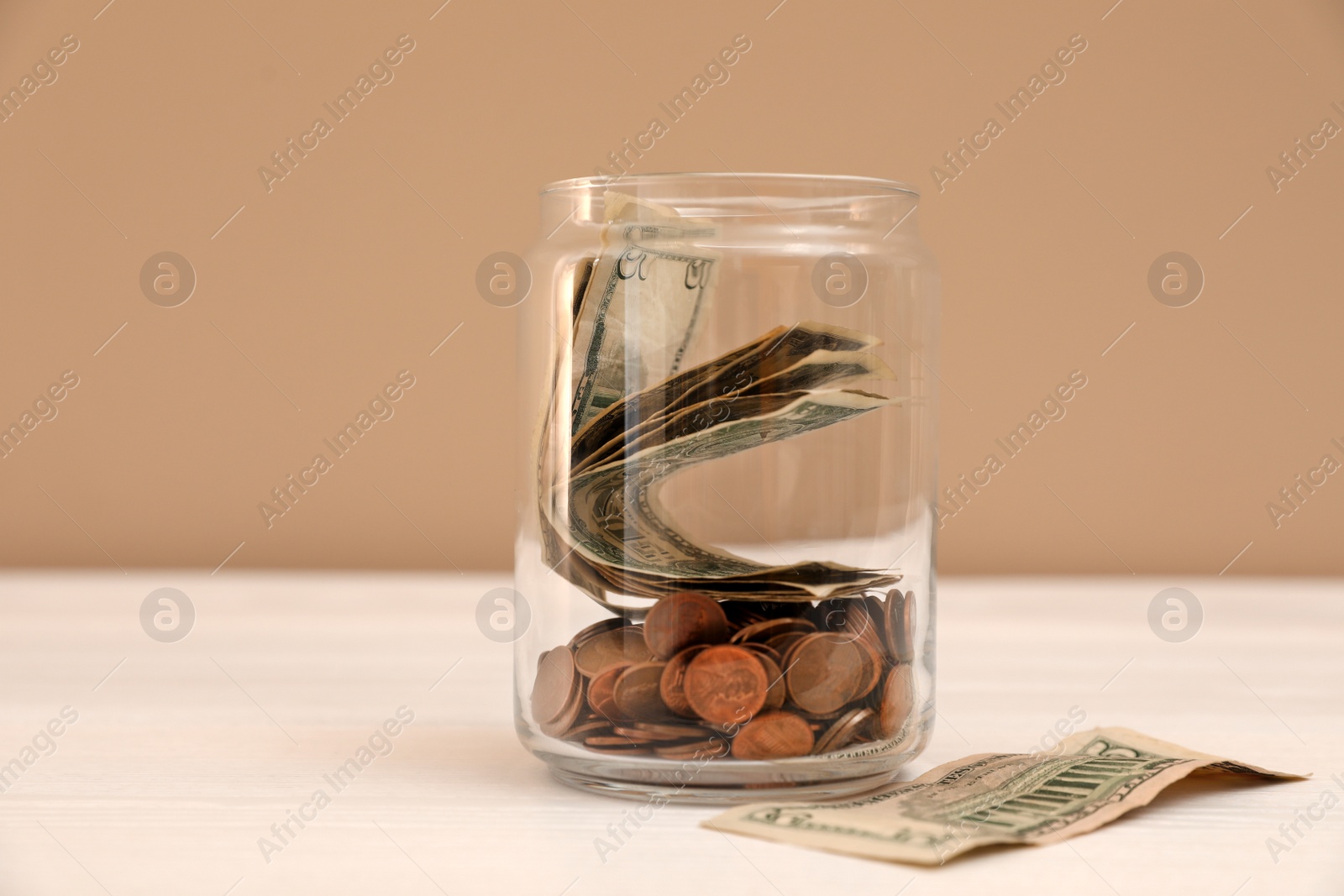 Photo of Donation jar with money on table against color background