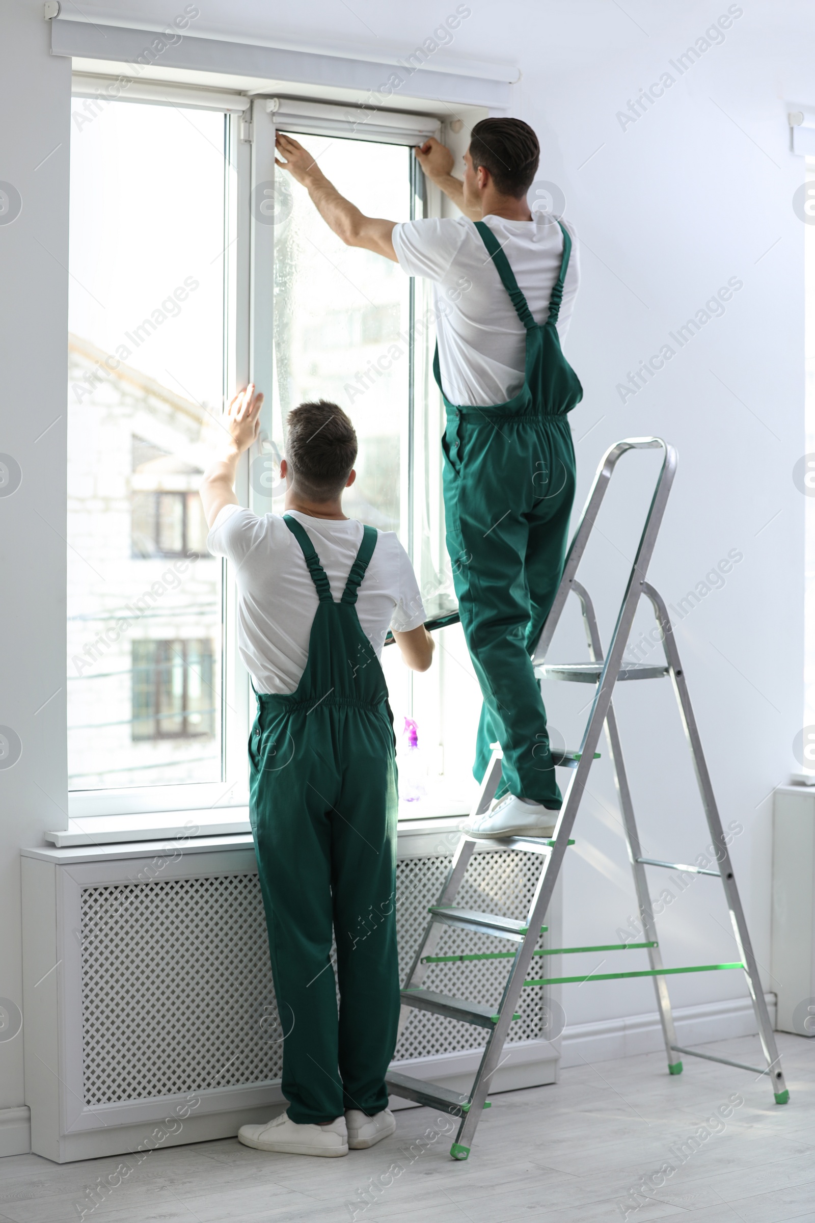 Photo of Professional workers tinting window with foil indoors