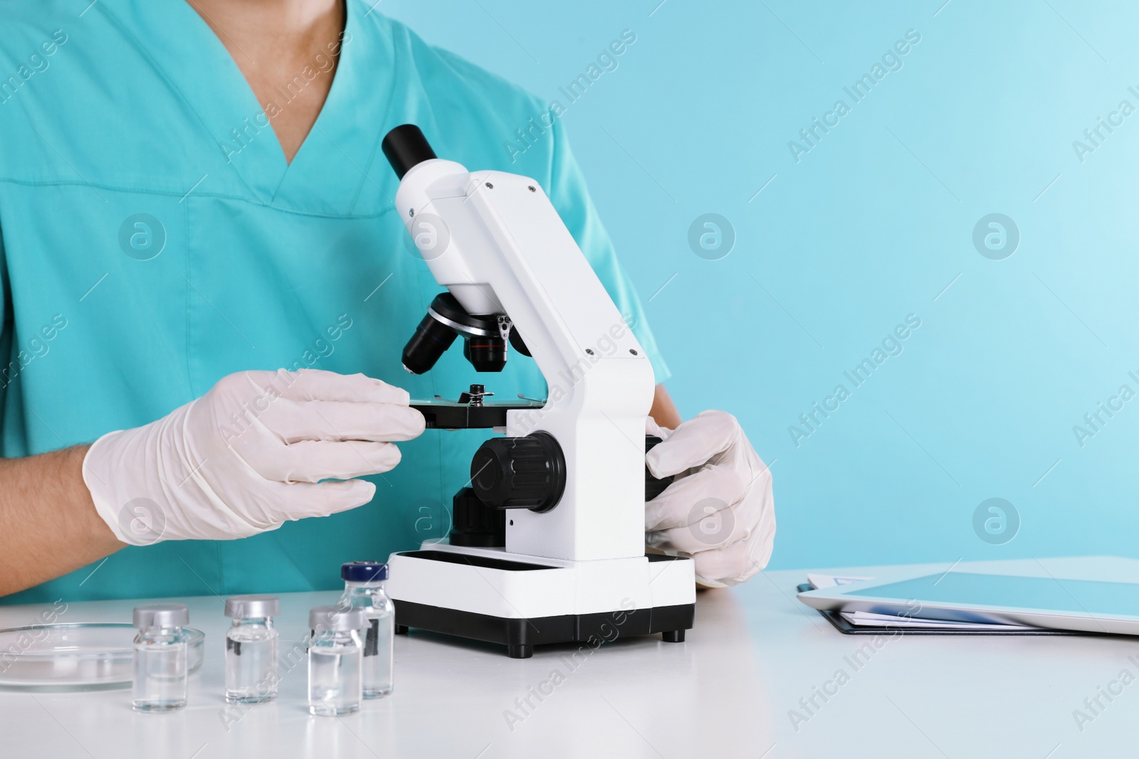 Photo of Male doctor using microscope at table, closeup with space for text. Medical object