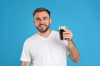 Photo of Handsome man with cold kvass on blue background. Traditional Russian summer drink