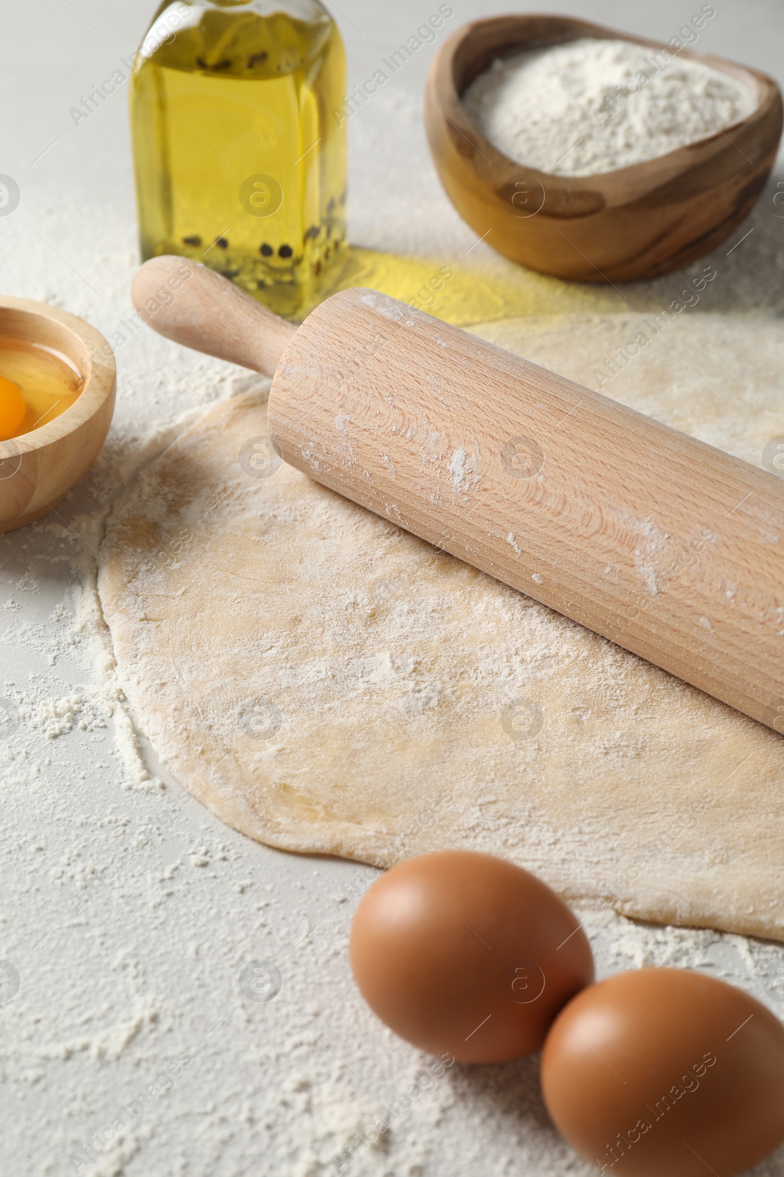 Photo of Raw dough, rolling pin and ingredients on table