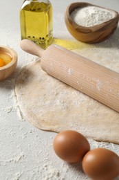 Photo of Raw dough, rolling pin and ingredients on table