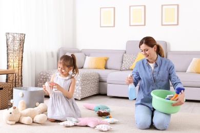 Housewife and daughter cleaning room together