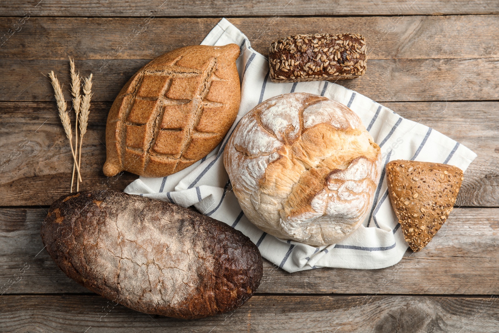 Photo of Different kinds of fresh bread on wooden table, flat lay.