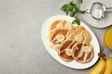 Photo of Tasty pancakes with sliced banana served on grey table, flat lay. Space for text
