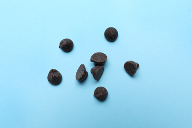 Delicious dark chocolate chips on light blue background, top view