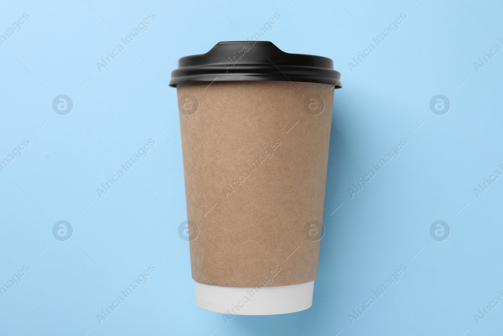 Photo of One paper cup on light blue background, top view. Coffee to go