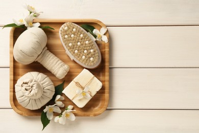 Beautiful jasmine flowers, herbal bags, brush and soap bar on white wooden table, top view. Space for text