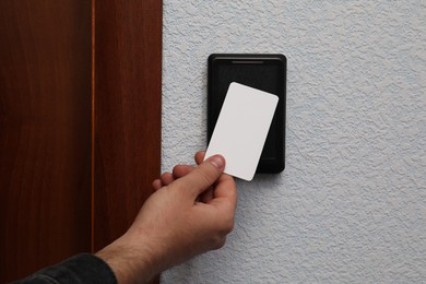 Photo of Man opening magnetic door lock with key card indoors, closeup