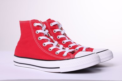 Photo of Pair of new red stylish high top plimsolls on white background