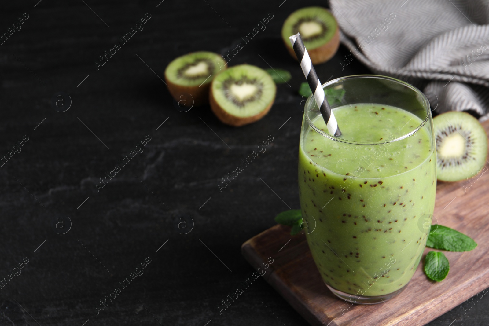 Photo of Delicious kiwi smoothie and fresh ingredients on black table, space for text