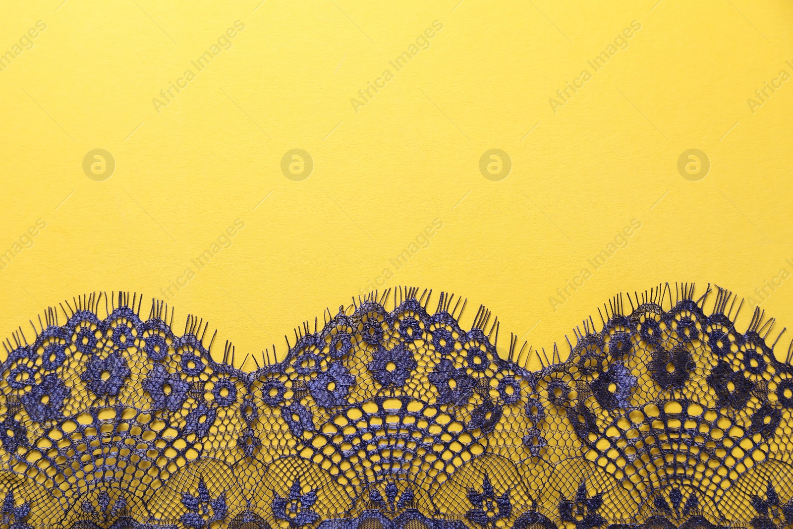 Photo of Blue lace on yellow background, top view. Space for text