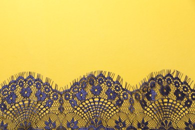 Blue lace on yellow background, top view. Space for text