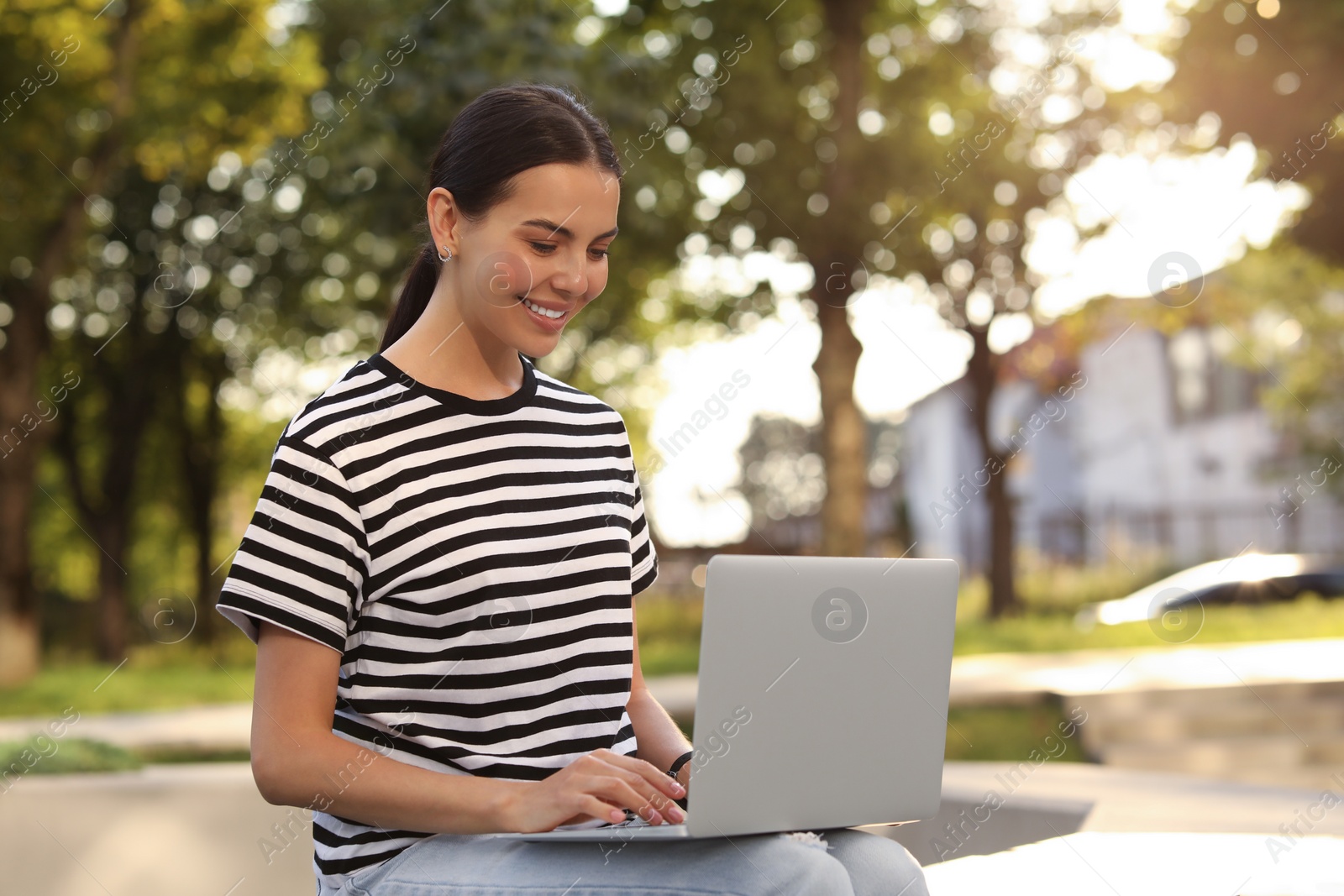 Photo of Happy young woman using modern laptop outdoors