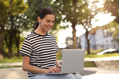 Photo of Happy young woman using modern laptop outdoors