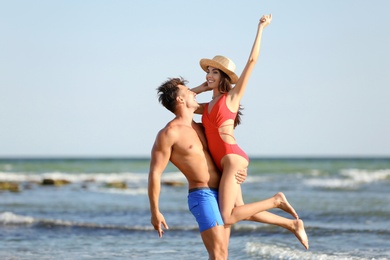 Happy young couple having fun at beach on sunny day