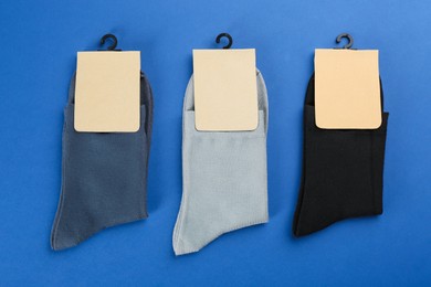Photo of Soft cotton socks on blue background, flat lay