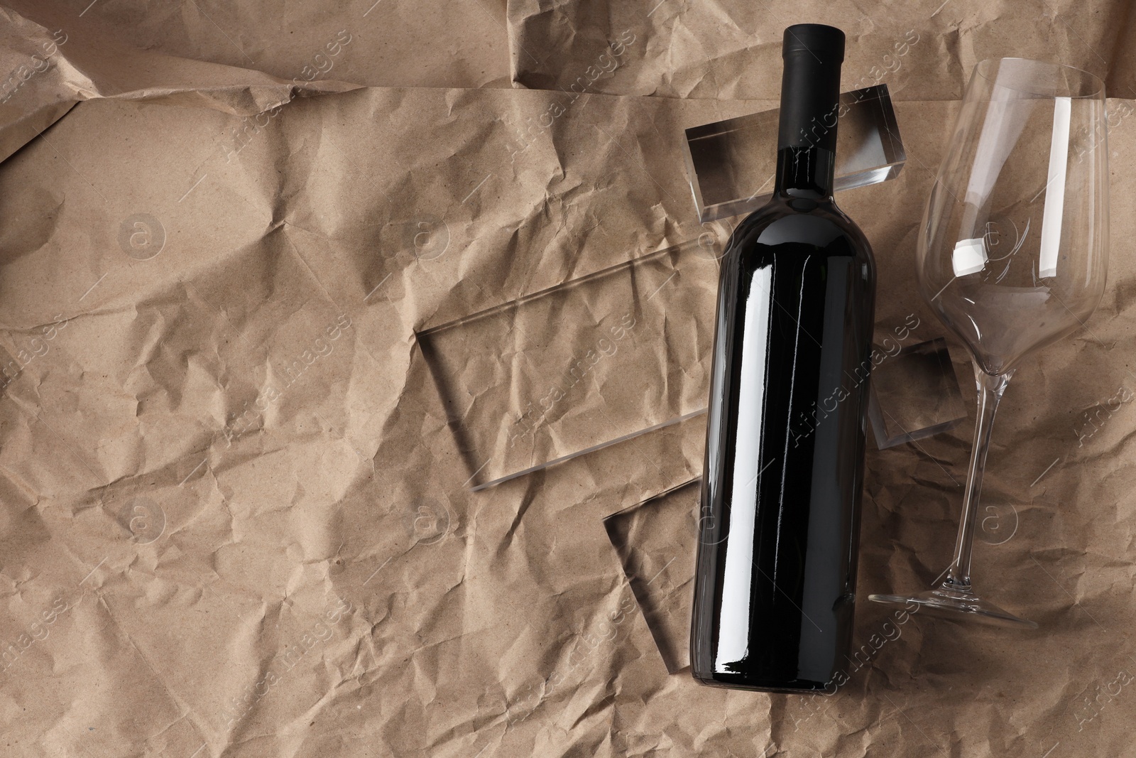 Photo of Stylish presentation of delicious red wine in bottle and glass on paper background, top view. Space for text