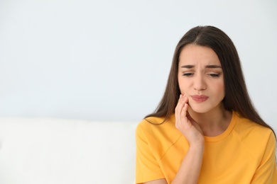 Photo of Young woman suffering from strong tooth pain at home, space for text