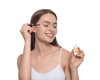 Young woman with eyelash oil on white background