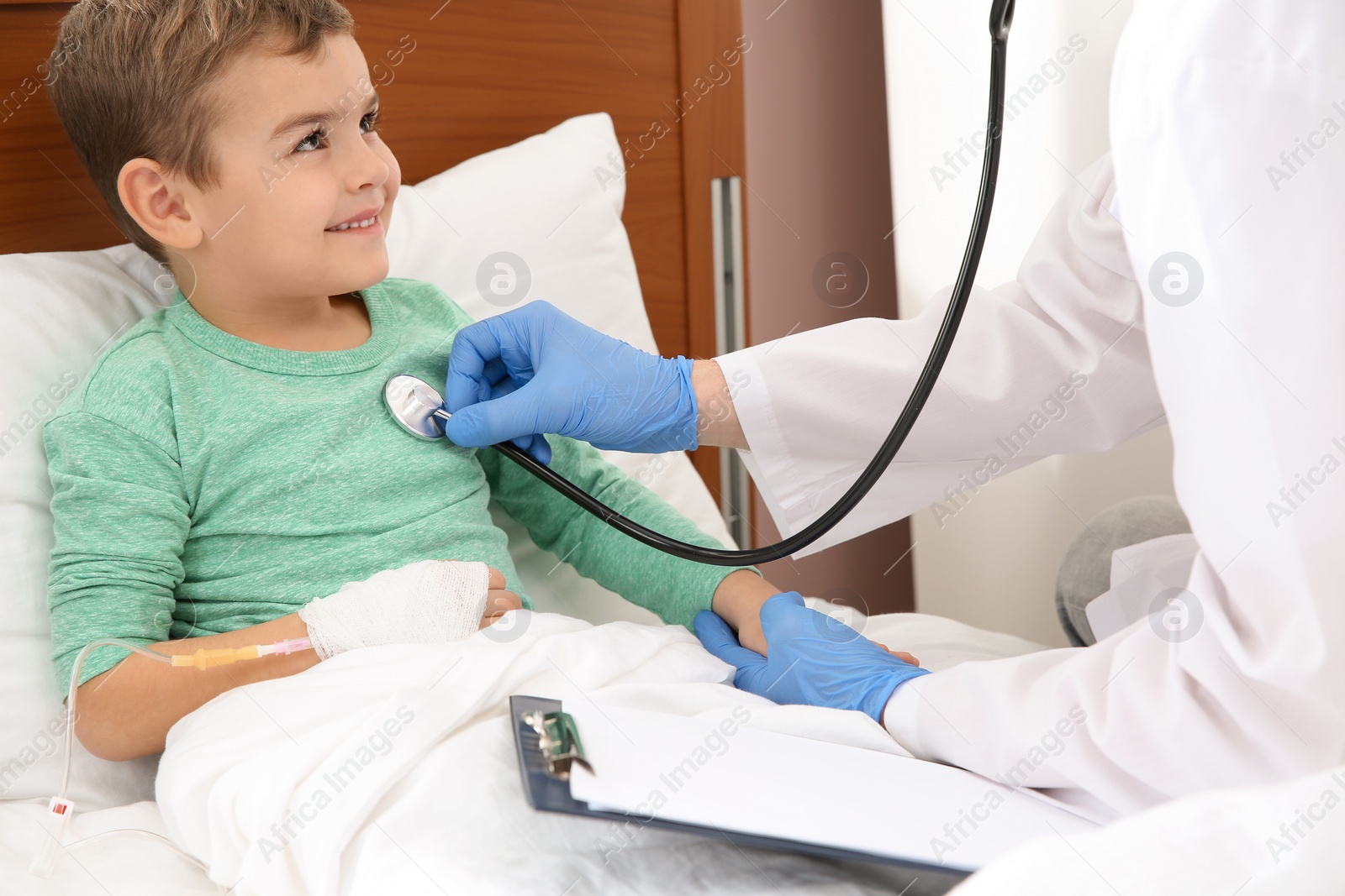 Photo of Doctor examining little child with stethoscope in hospital