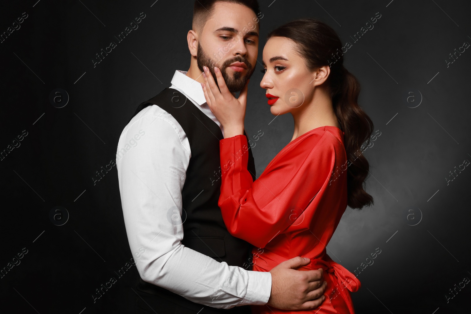 Photo of Handsome bearded man with sexy lady on dark background