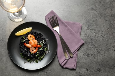 Delicious black risotto with shrimps served on grey table, flat lay