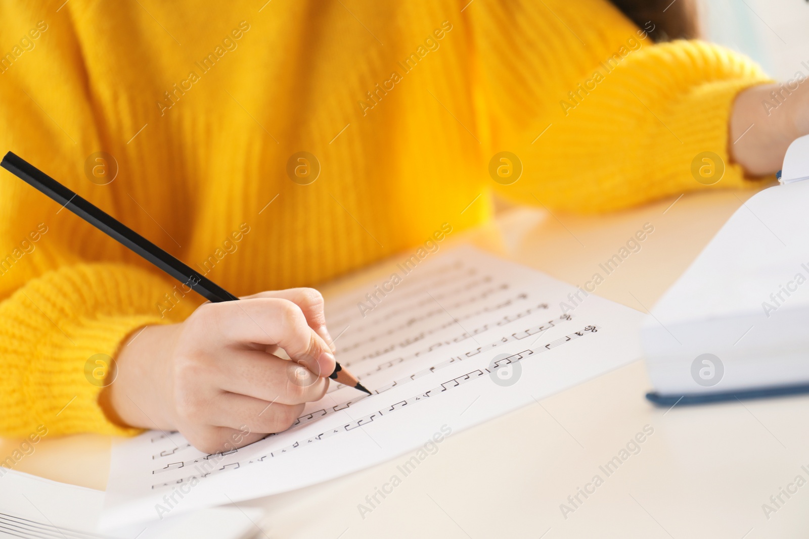 Photo of Child writing music notes at table, closeup